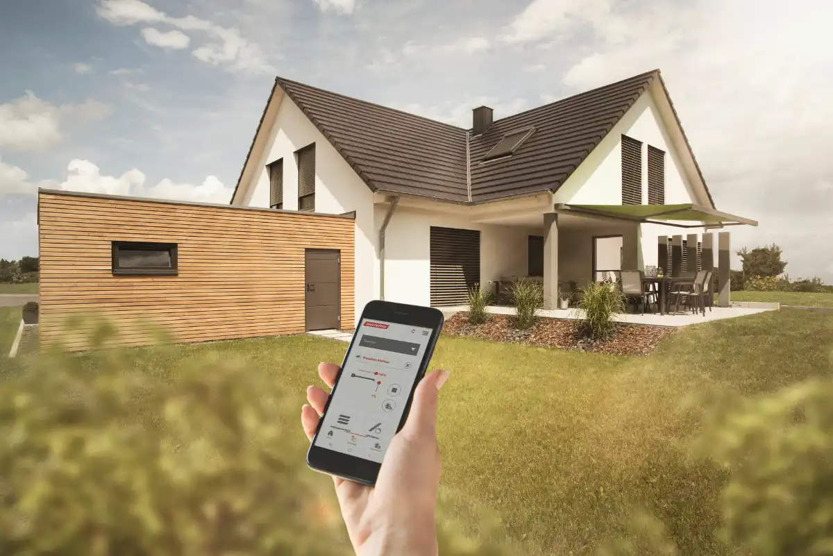 Smart Home Steuerung mit Smartphone vor modernem Einfamilienhaus